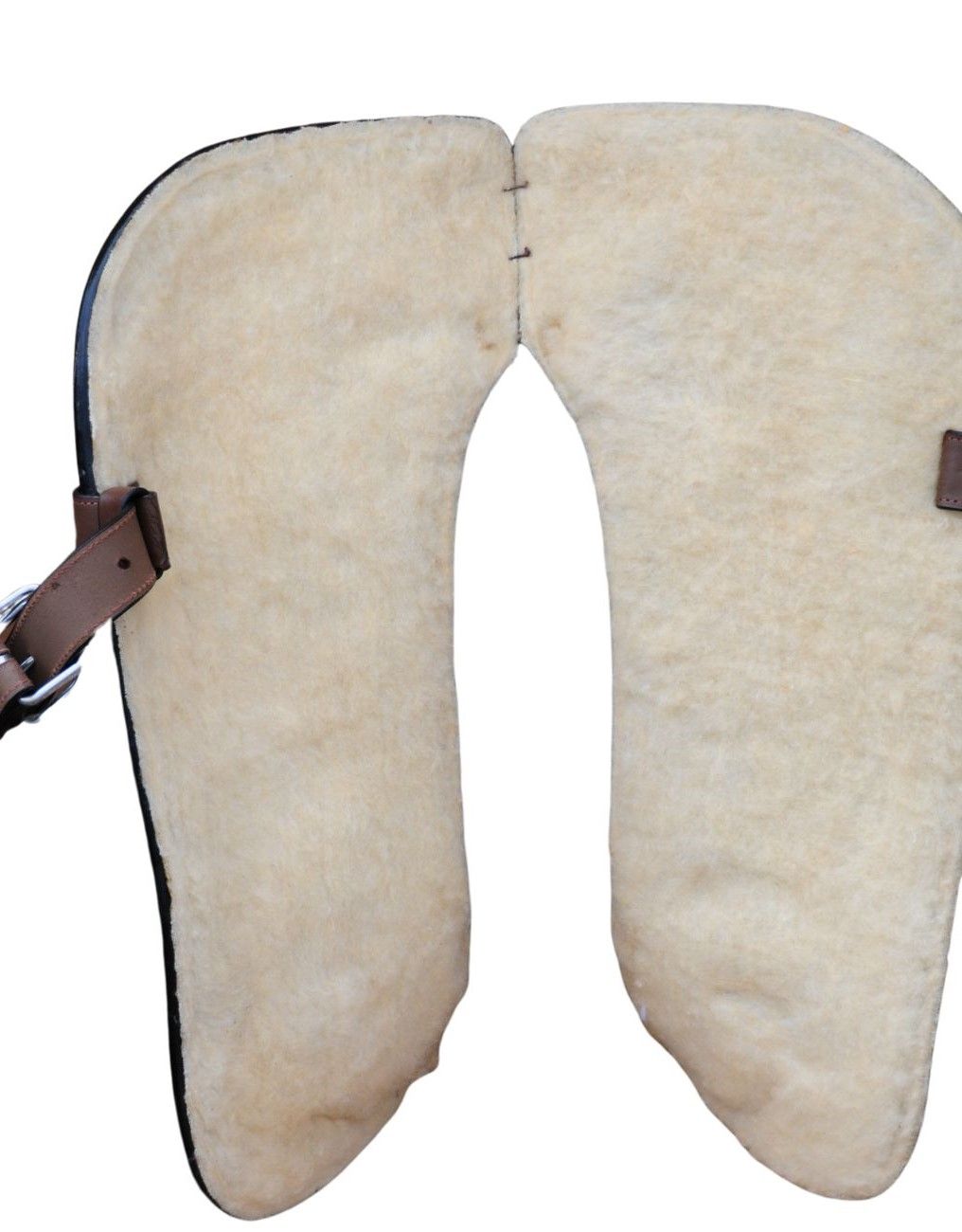 Sattelunterlage aus beigem Fell. Zwei getrennte, gebogene Teile mit Lederriemen.