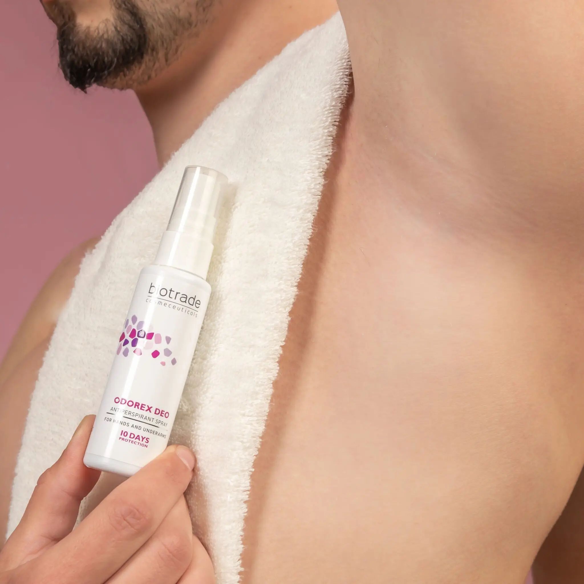 Person hält eine weiße Sprühflasche. Beschriftung: Biotrade, Odorex Deo, Antitranspirant Spray. 10 Tage Schutz. Arm unter Handtuch.