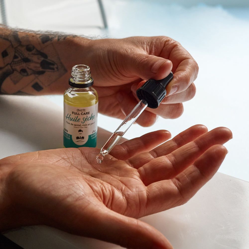 Klarflüssiges Öl in einer Glasflasche mit Pipette. Eine Pipette wird über eine Hand gehalten, die andere hält die Flasche.