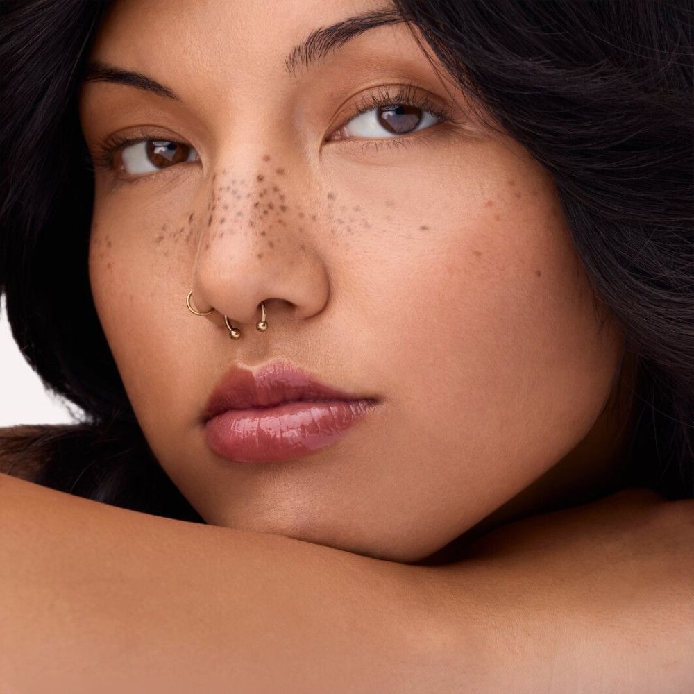 Porträt einer Frau mit Lippen, die mit Lipgloss bedeckt sind. Die Lippen sind rotbraun.