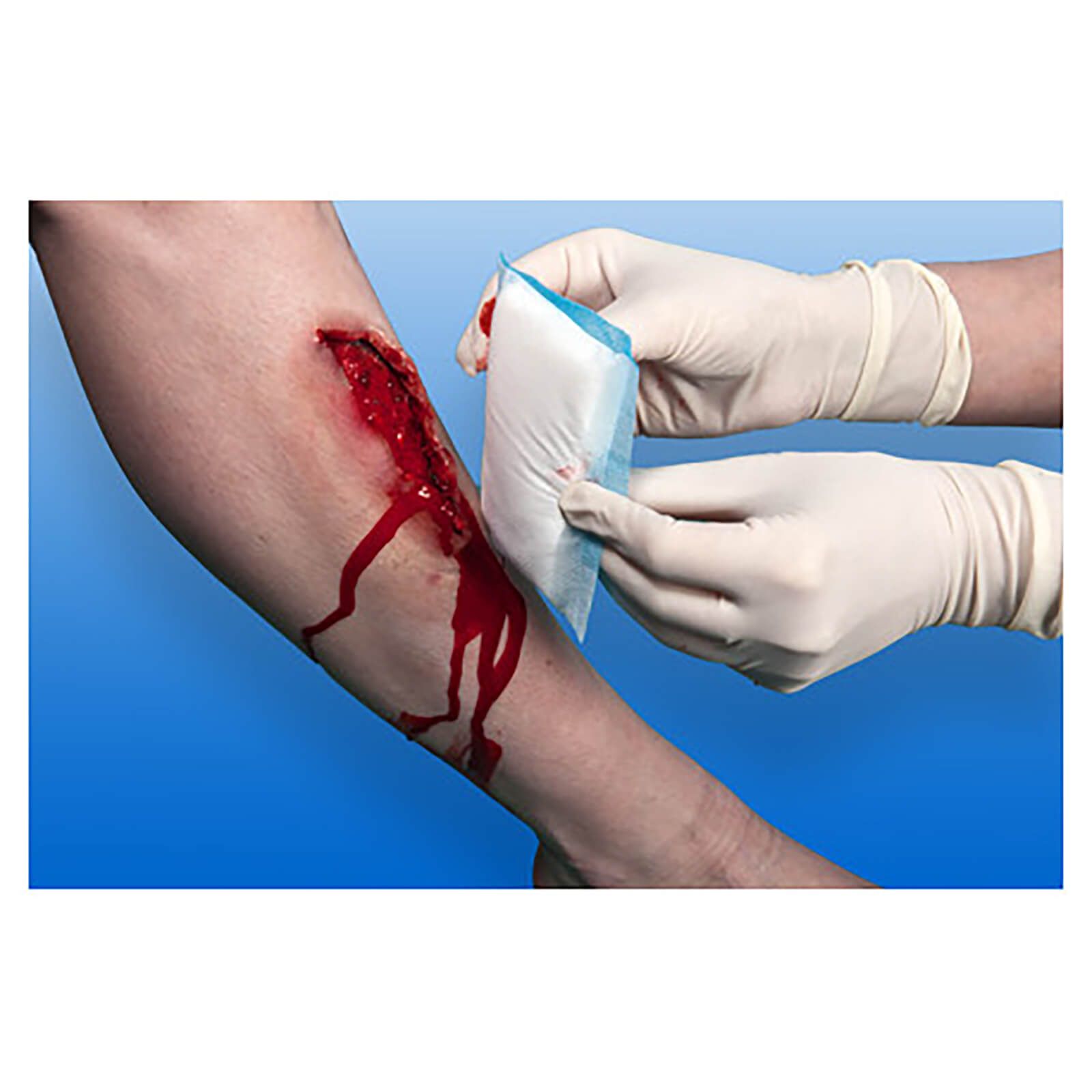 Person hält sterile Saugkompresse an blutende Wunde am Arm. Handschuhe. Hintergrund blau.
