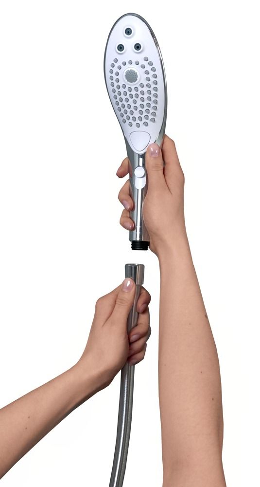 Handbrause mit Schlauch, wird von Händen gehalten. Der Brausekopf hat drei Düsen und eine zentrale Fläche mit kleinen Löchern.