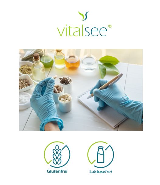 Person mit Handschuhen hält Kapseln. Laborutensilien und Zutaten auf dem Tisch. Glutenfrei und laktosefrei Symbole.