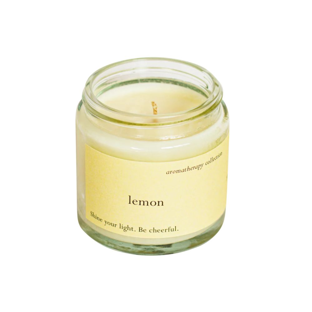 Kerze in einem Glas. Auf dem Etikett steht "lemon" und "aromatherapy collection". Der Text lautet: "Shine your light. Be cheerful."