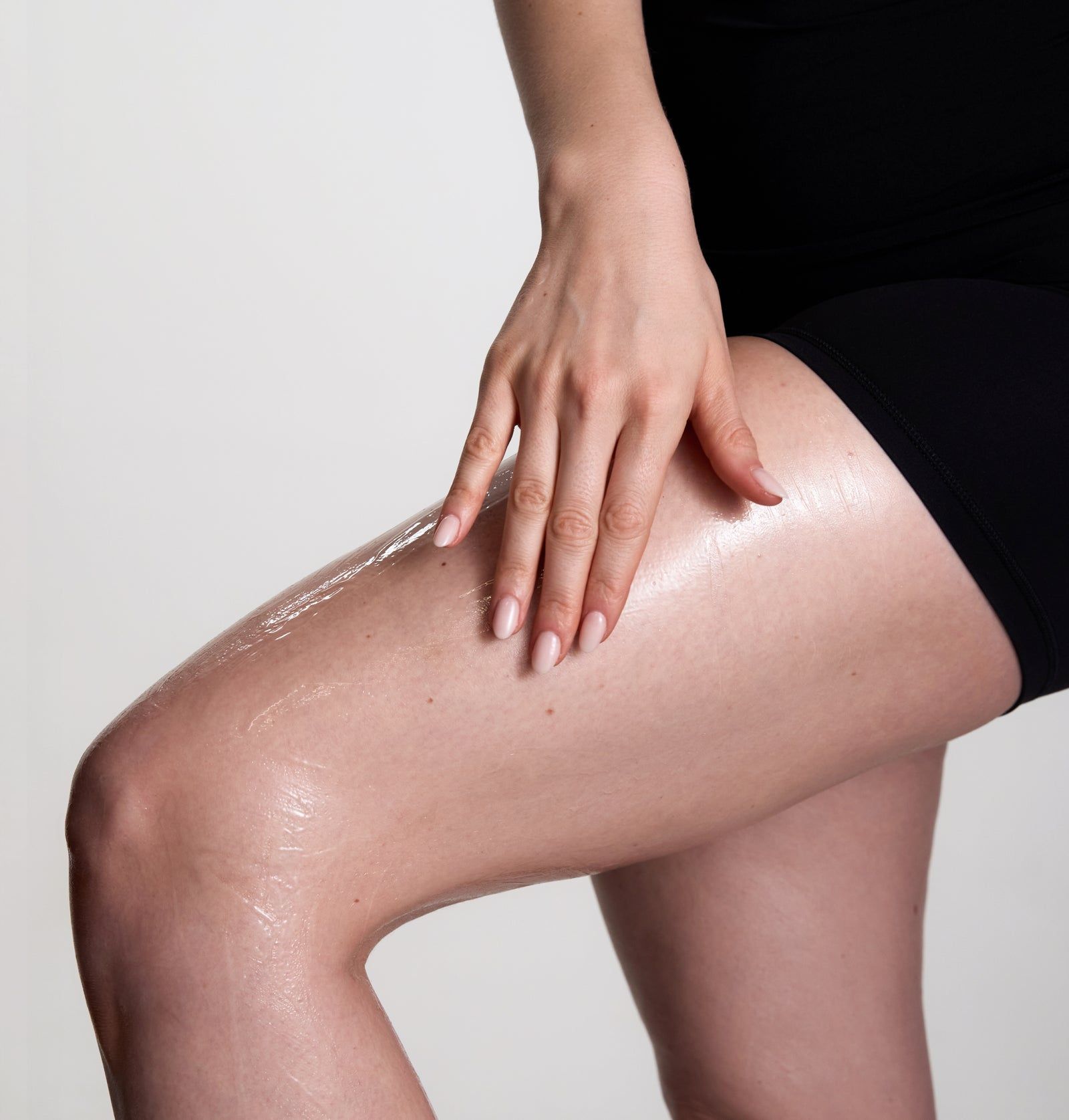 Person reibt Gel auf Oberschenkel. Gel ist transparent. Person trägt schwarze Shorts.
