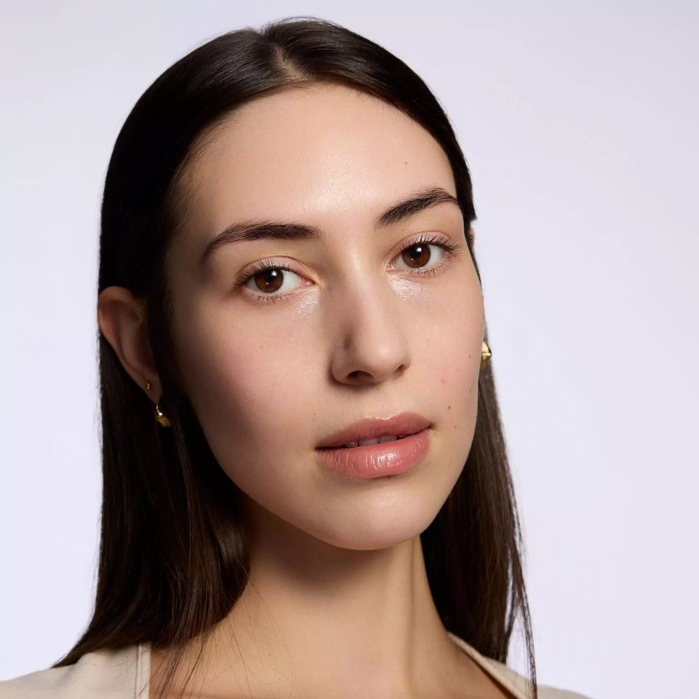 Porträt einer Frau. Natürliches Make-up. Helle Haut, dunkle Haare, goldene Ohrringe.