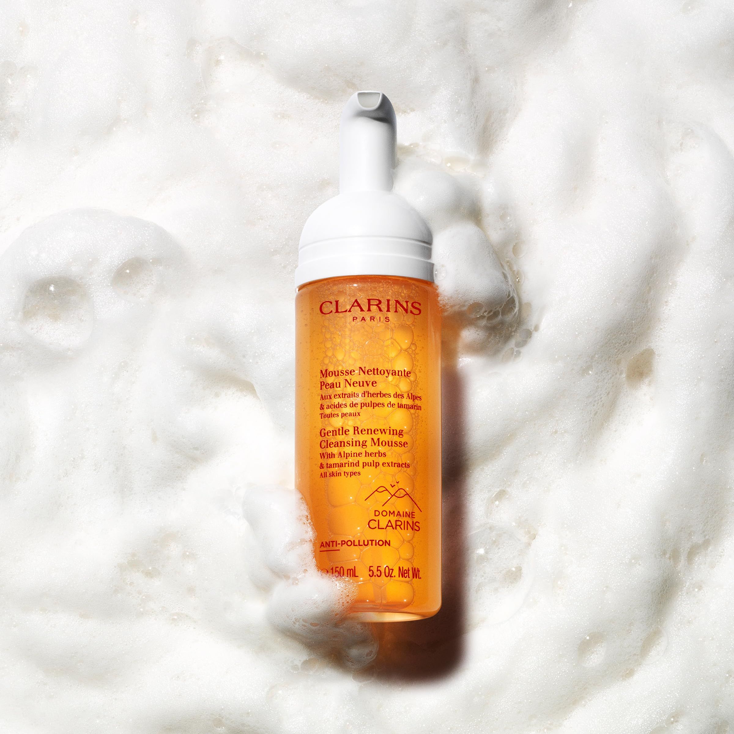 Clarins Reinigungsmousse in Schaum. Flasche mit weißem Pumpkopf. Gelbliche Flüssigkeit. Text: Mousse Nettoyante Peau Neuve, Gentle Renewing Cleansing Mousse.