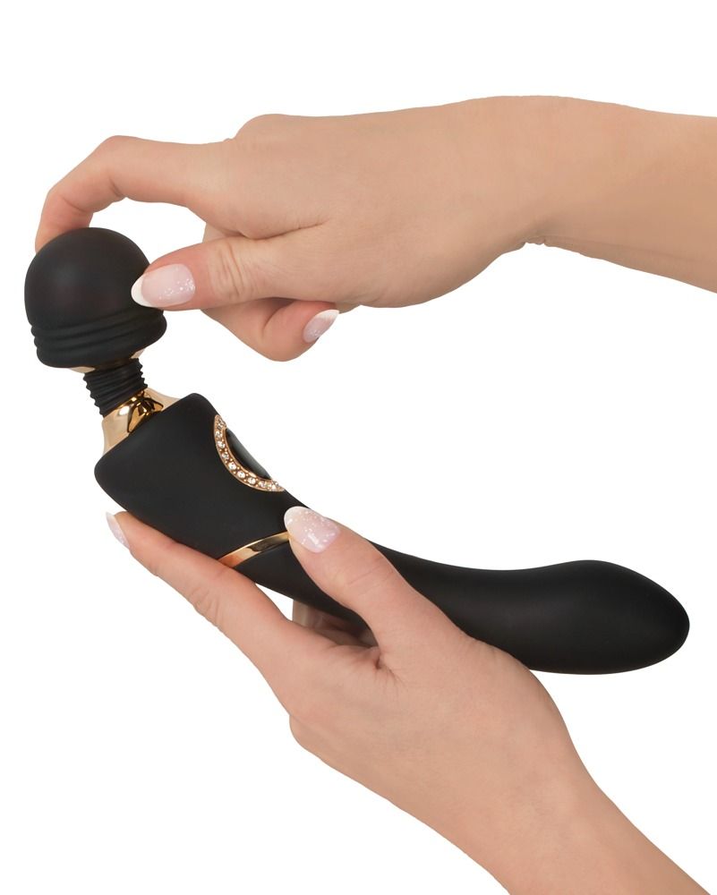 Hände passen Kopf an schwarzen Vibrator mit goldener Verzierung an.