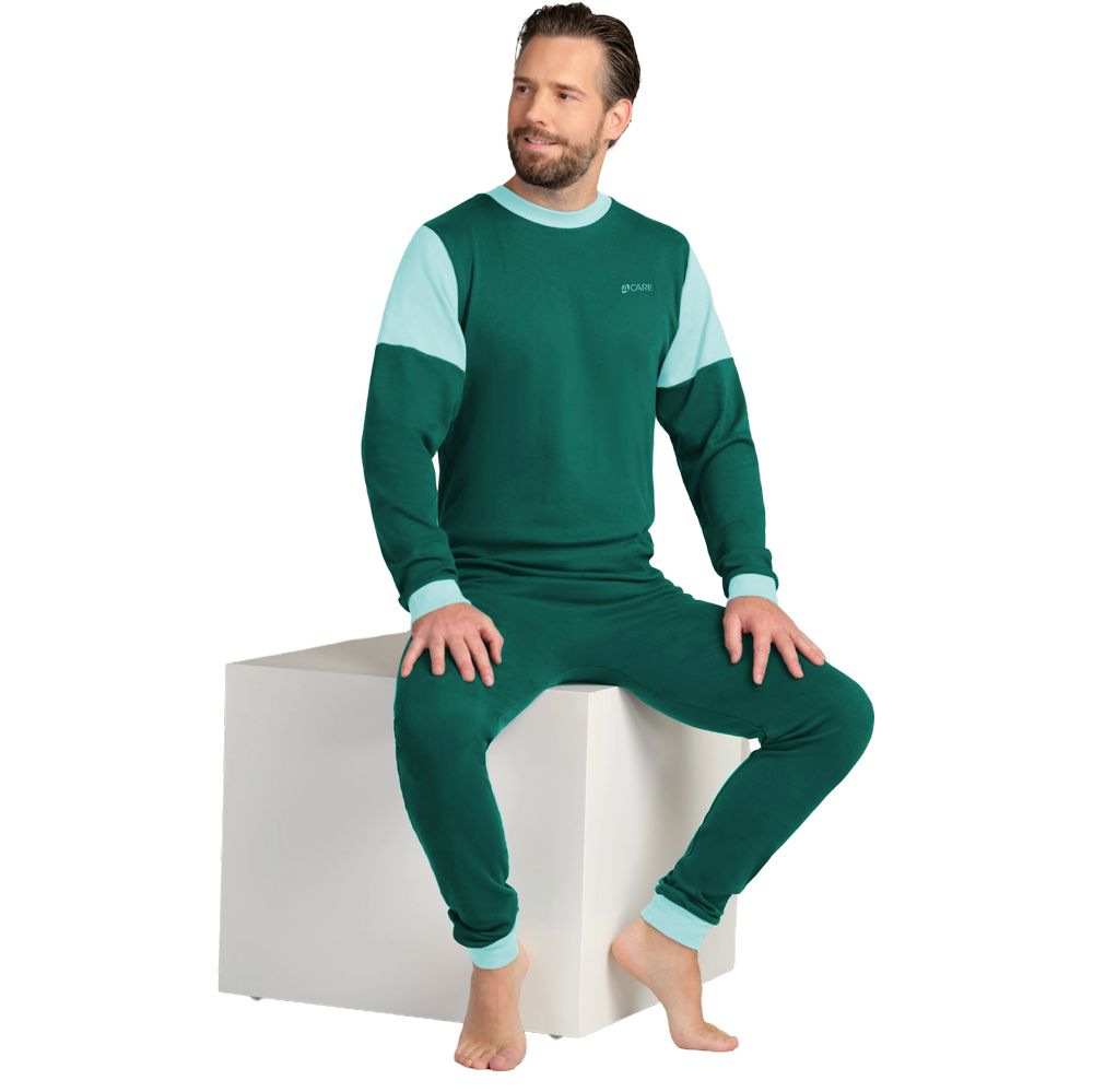 Grüner Overall mit hellblauen Akzenten. Langärmlig, mit Rundhalsausschnitt und Rückenreißverschluss. Mann sitzt auf weißem Würfel.