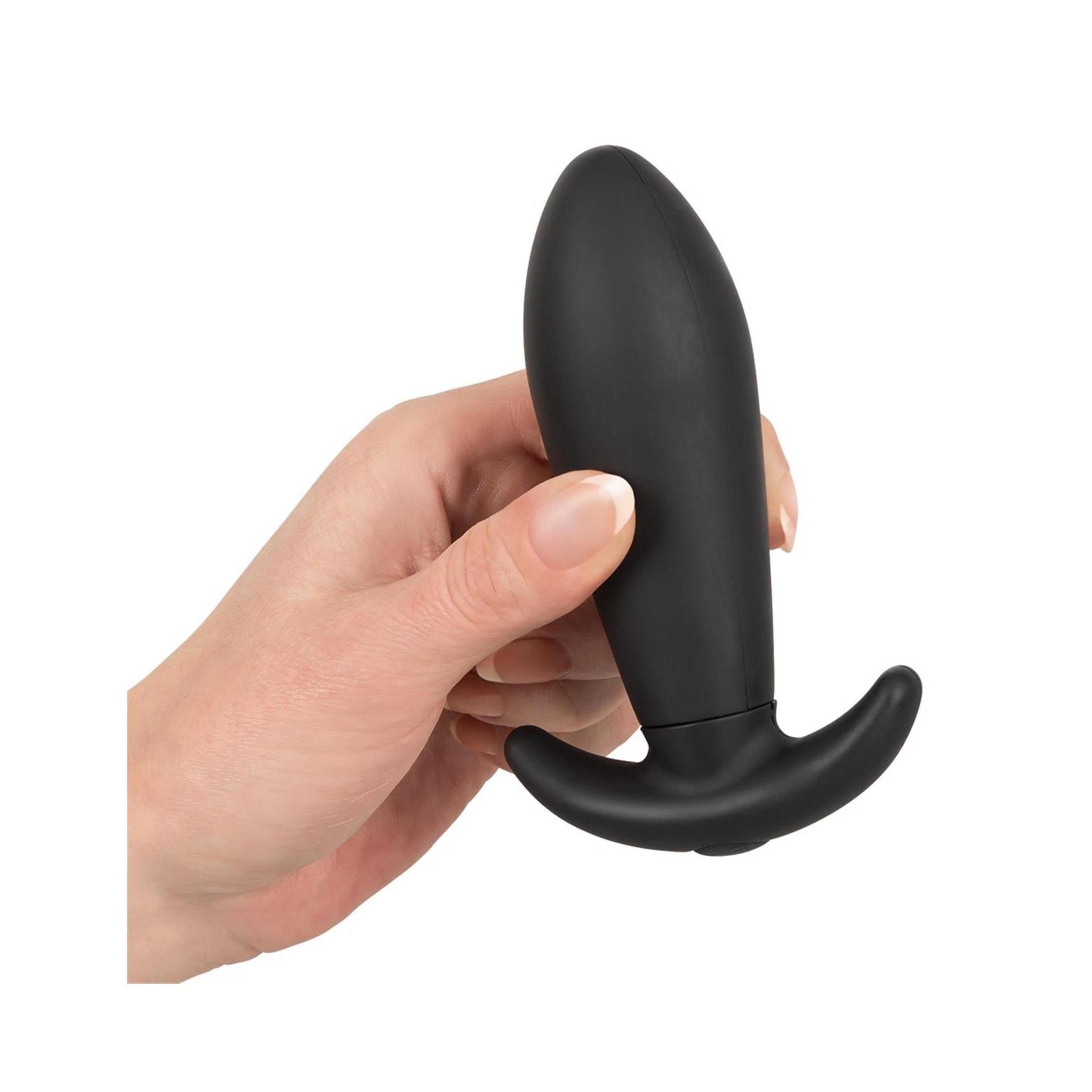 Hand hält einen schwarzen Anus-Plug. Der Plug hat eine gebogene Form mit einem Griff. Der Hintergrund ist weiß.