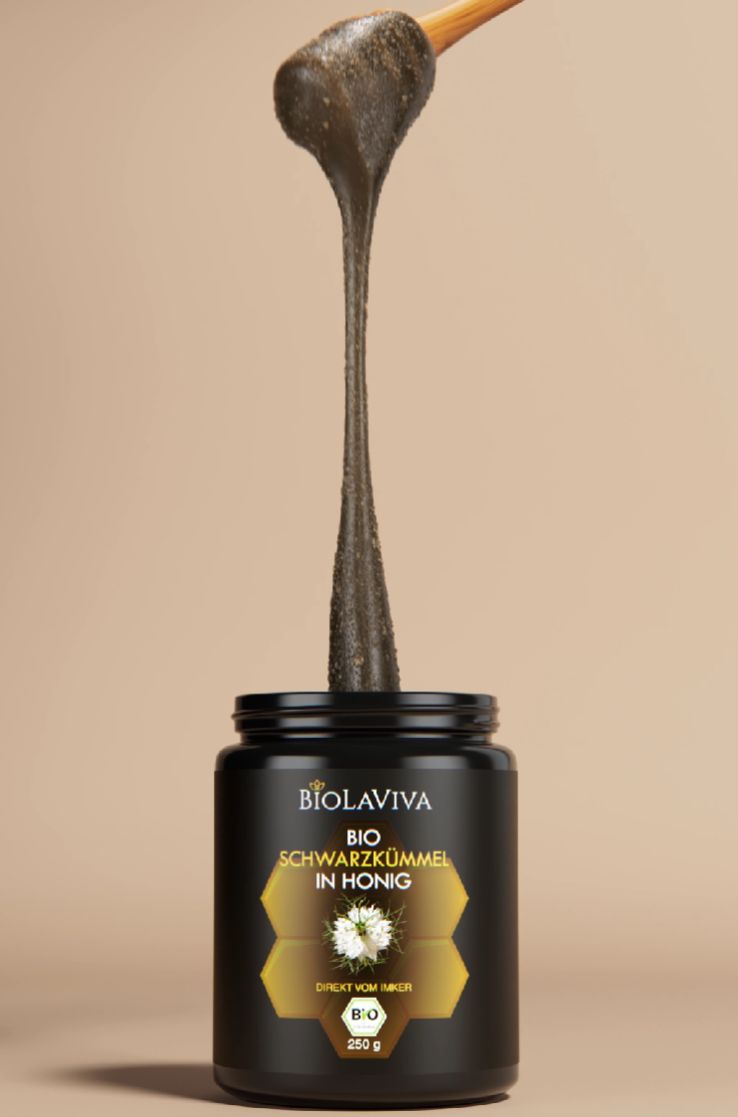 Schwarzkümmel in Honig wird mit einem Löffel aus dem schwarzen Glas entnommen. BIOLAVIVA Logo.