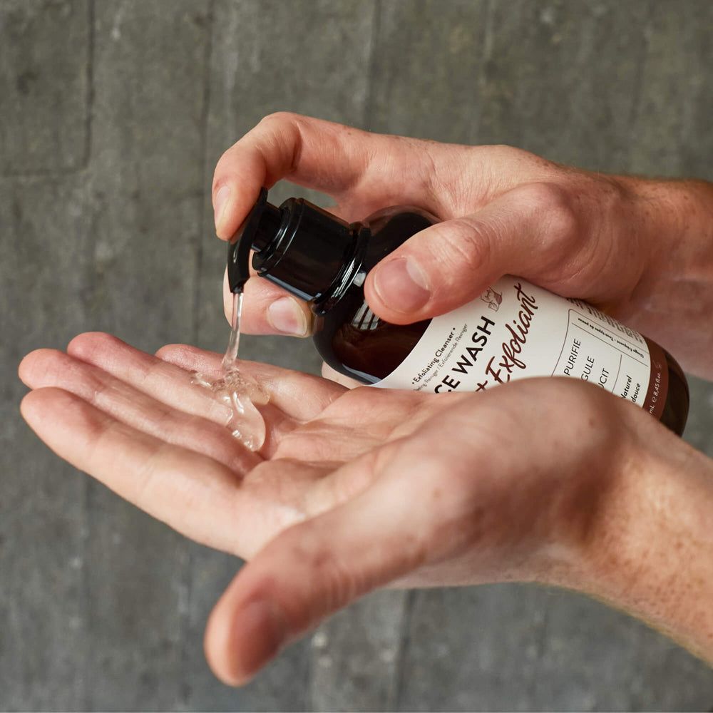 Braune Flasche mit schwarzem Pumpverschluss. Eine Hand hält die Flasche, die andere fängt das transparente Gel auf.