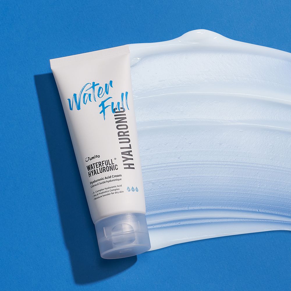 Weiße Tube mit blauem Schriftzug "Water Full Hyaluronic" auf blauem Untergrund. Creme daneben.