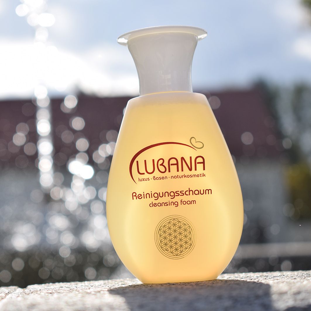 Beige Flasche mit weißem Verschluss. Aufschrift: Lubana Reinigungsschaum. Logo mit Herz. Luxus-Basen-Naturkosmetik. Im Freien.