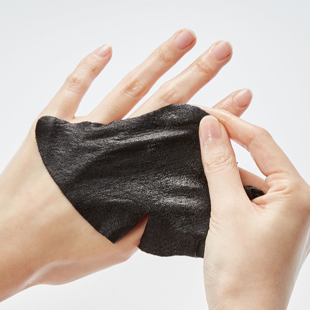 Hände halten eine schwarze Gesichtsmaske. Die Maske ist aus schwarzem Material gefertigt und leicht feucht.