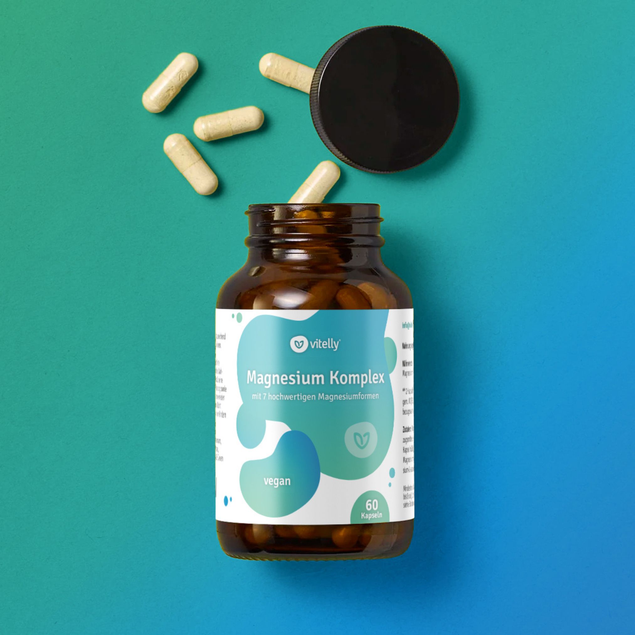 Braune Glasflasche mit Kapseln und offenem Deckel. Aufschrift: Magnesium Komplex, vegan, 60 Kapseln. Kapseln verstreut.