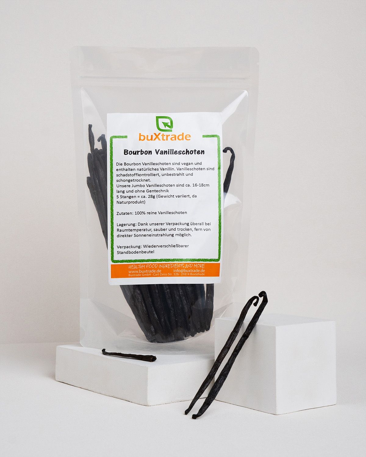 Transparente Verpackung mit Vanilleschoten und Etikett. Zwei Schoten liegen daneben. Text: buXtrade Bourbon Vanilleschoten.