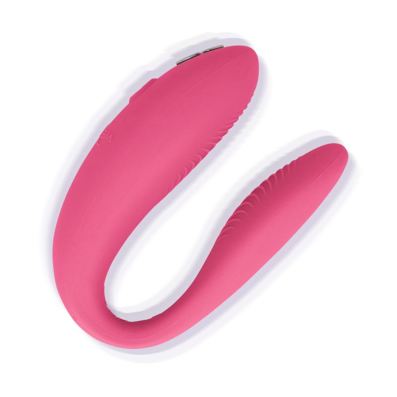 Rosa Vibrator mit geschwungener Form. Oberseite mit geriffelter Textur. Auf weißem Hintergrund.