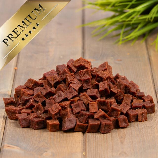Haufen brauner, würfelförmiger Snacks. Goldene Plakette mit der Aufschrift 'PREMIUM' und fünf Sternen.