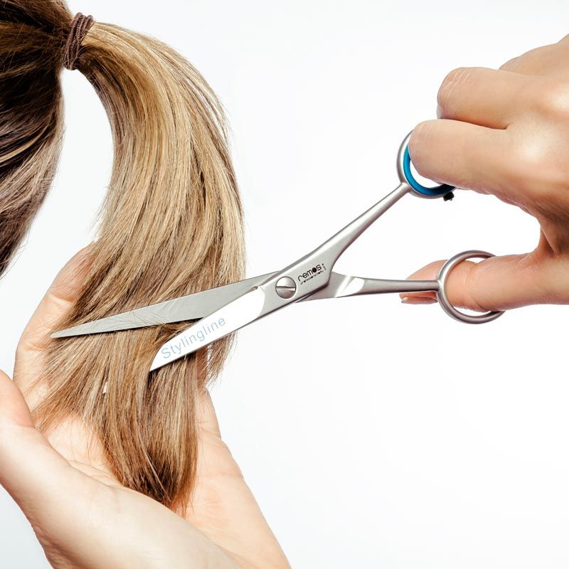 Person schneidet mit gezahnter Edelstahlschere eine Haarsträhne.