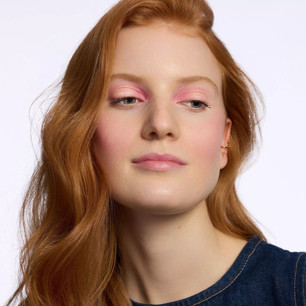 Porträt einer Frau mit rosa Lidschatten. Rotes Haar, blaue Jeansjacke. Hautton: hell.