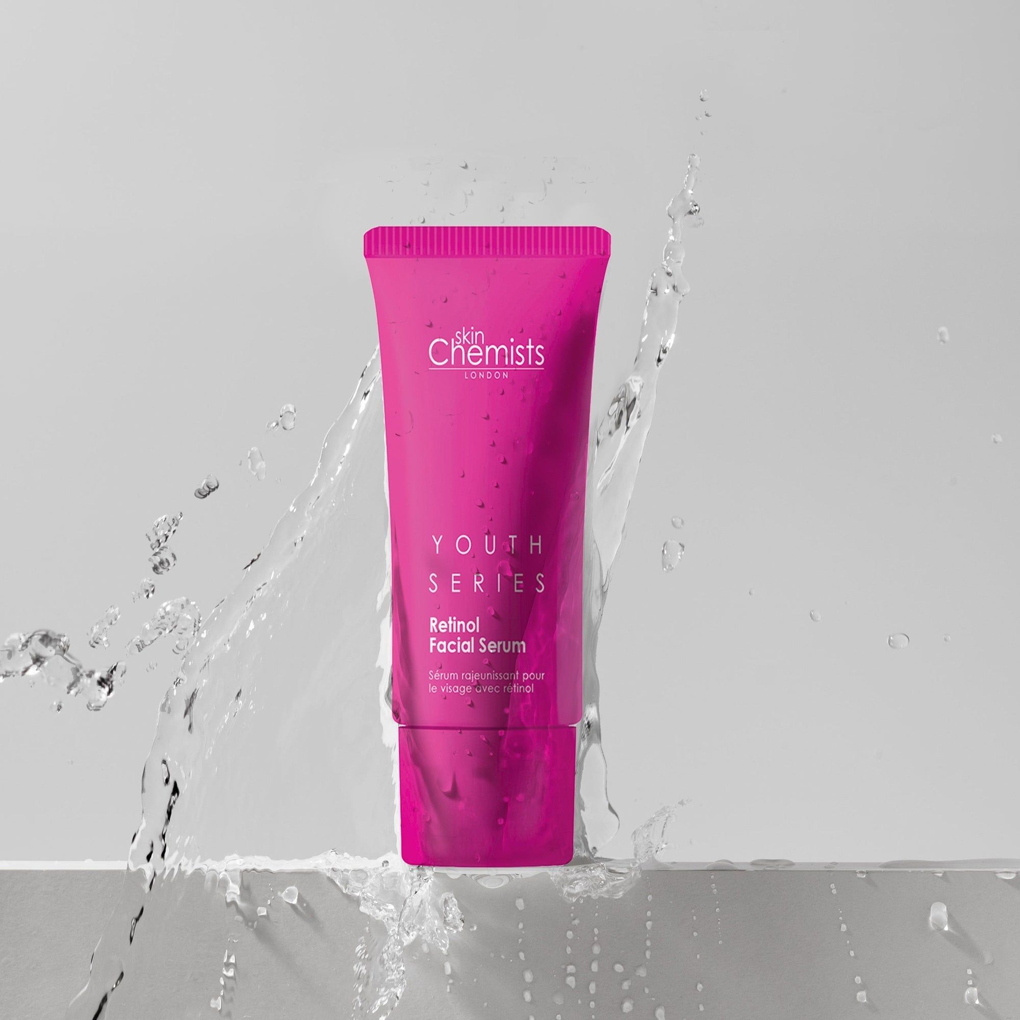 Rosa Tube mit "skinChemists" und "YOUTH SERIES Retinol Facial Serum" vor Wasser. Englische und französische Beschriftung.