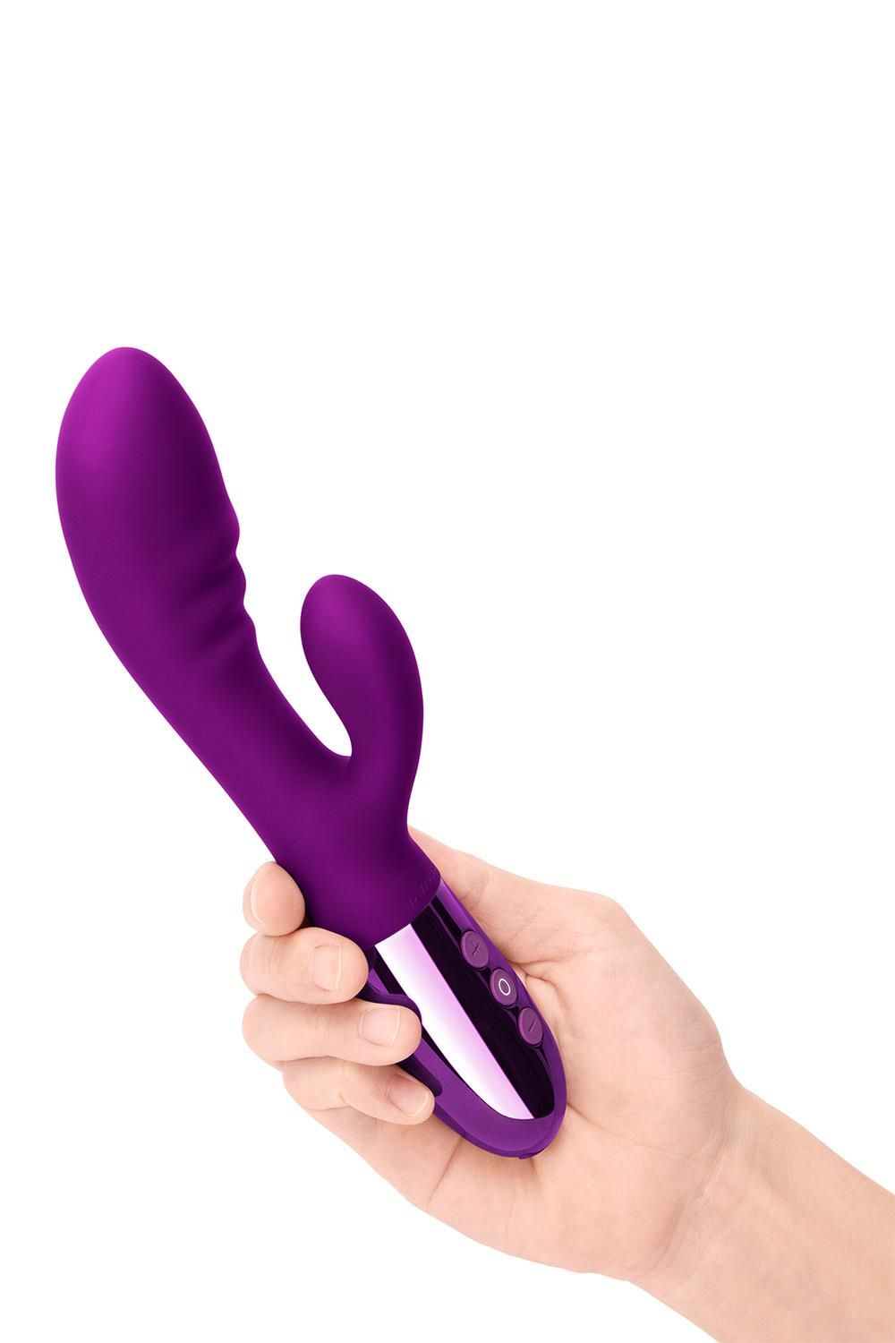 Hand hält einen lila Vibrator. Das Gerät hat eine gebogene Form, zwei Aufsätze und drei Knöpfe.