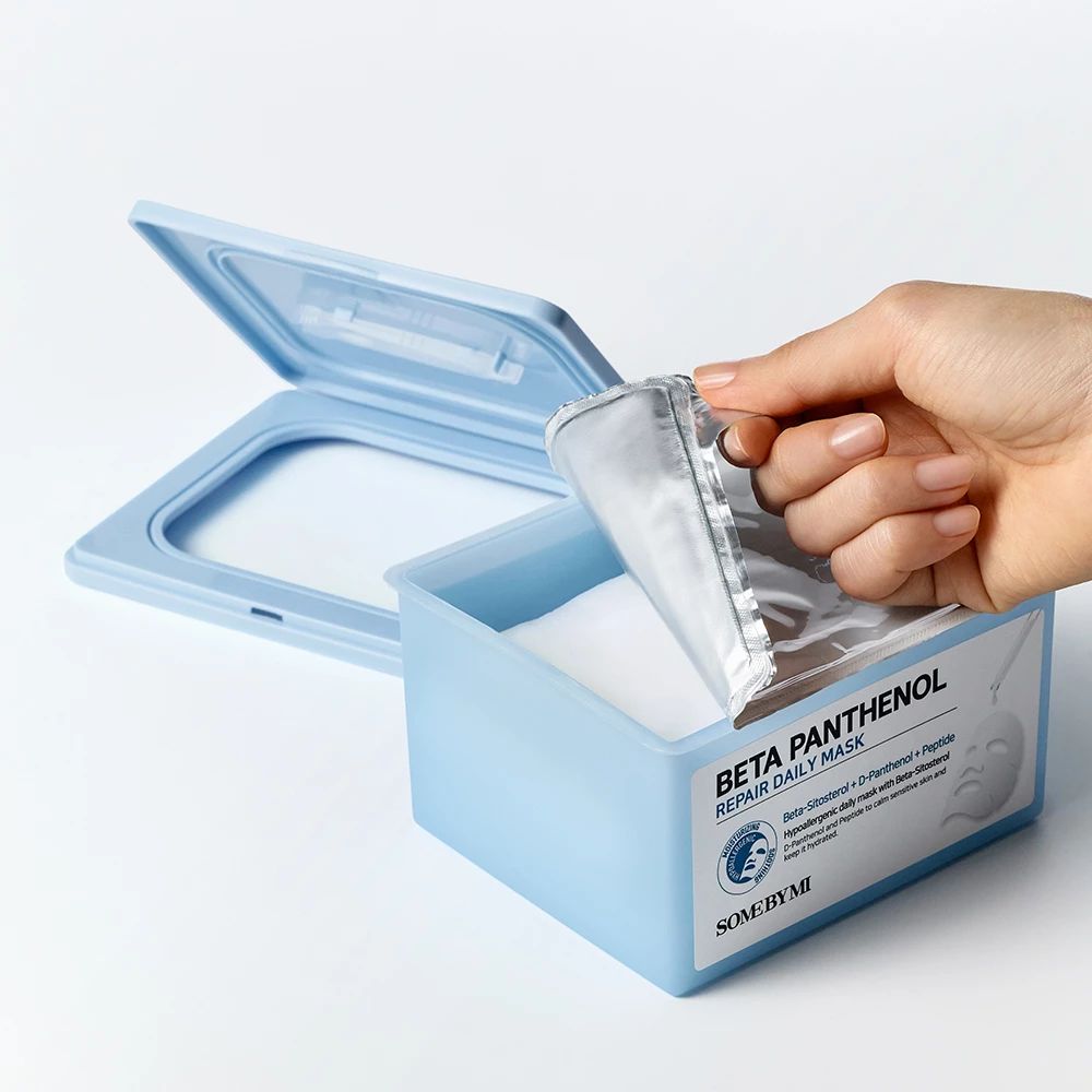 Blaue Box mit Deckel, Hand entnimmt Maske. Aufschrift: Beta Panthenol Repair Daily Mask. SOME BY MI Logo.