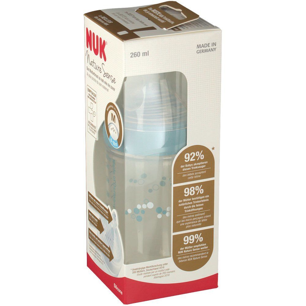 Babyflasche in Verpackung. Marke NUK, Nature Sense. Flasche aus Silikon, blau. Verpackung mit Produktinformationen und Prozentangaben.