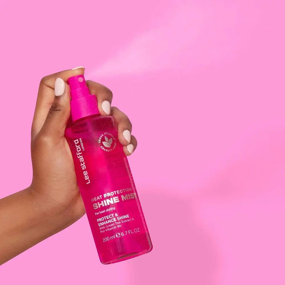 Hand hält Lee Stafford Hitzeschutz Glanzspray, Sprühnebel wird freigesetzt.