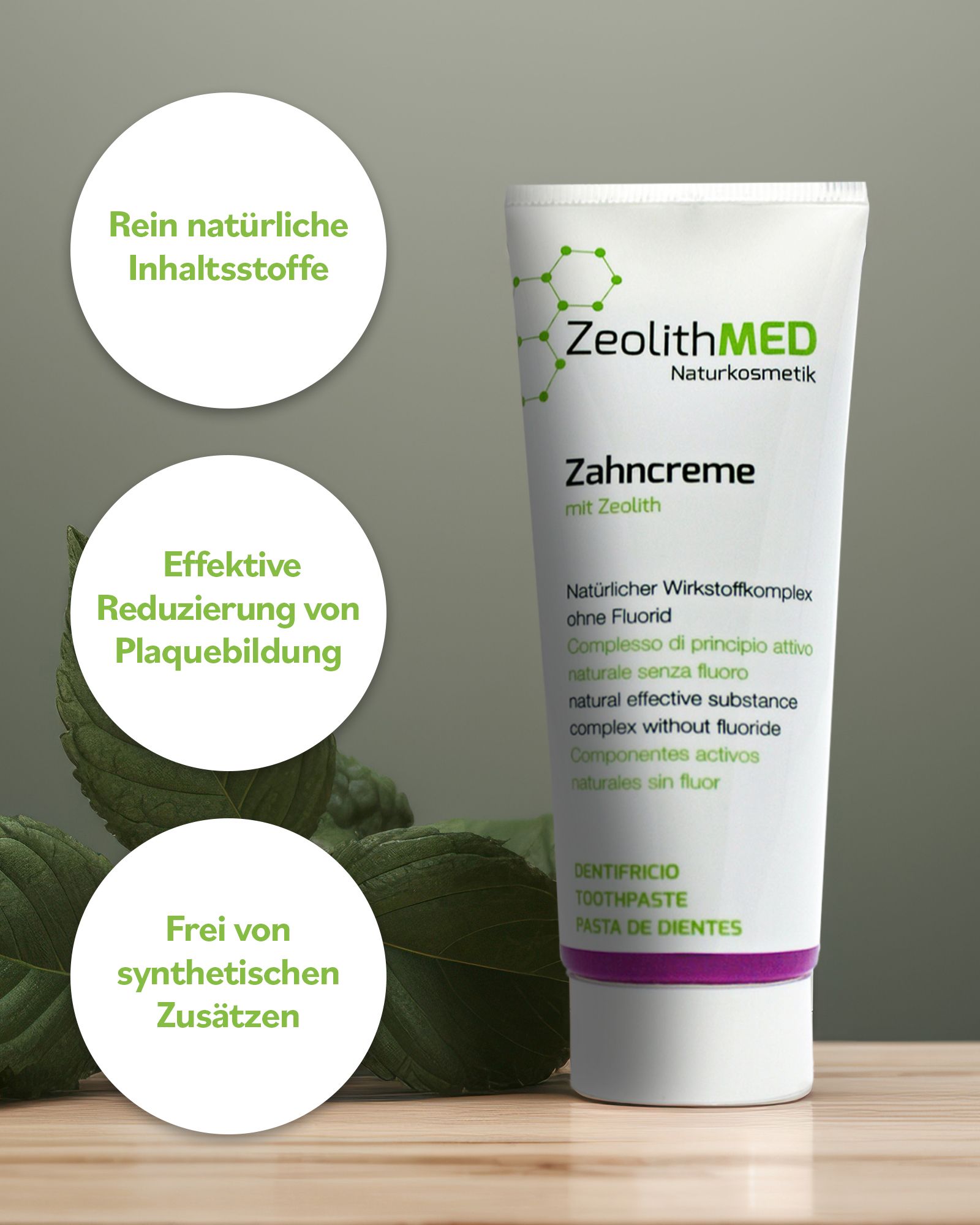 Zahncreme-Tube, weiß mit lila Akzenten. Text: ZeolithMED, Zahncreme ohne Fluorid. Zusätzliche Grafiken und Blätter.