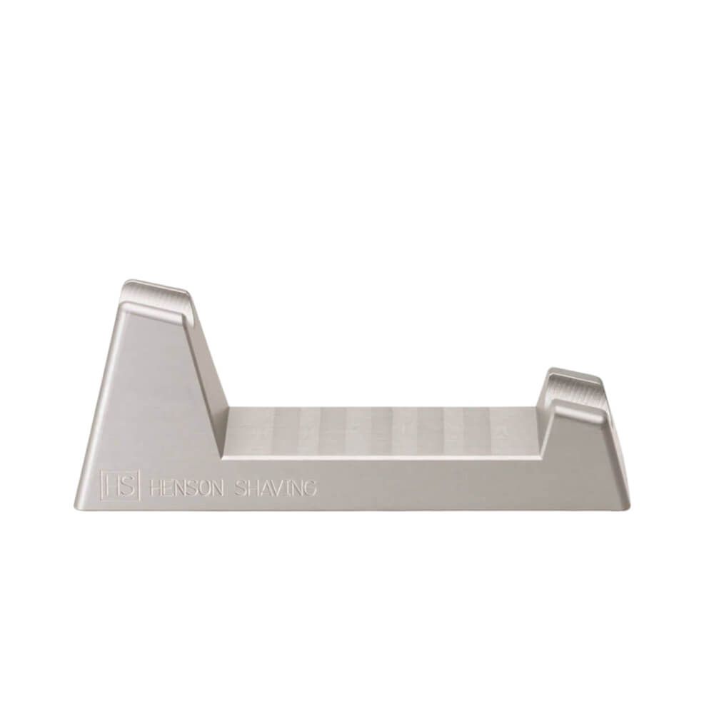 Silberfarbene Rasiererhalterung. Aufschrift: HENSON SHAVING. Schräge Ablagefläche.