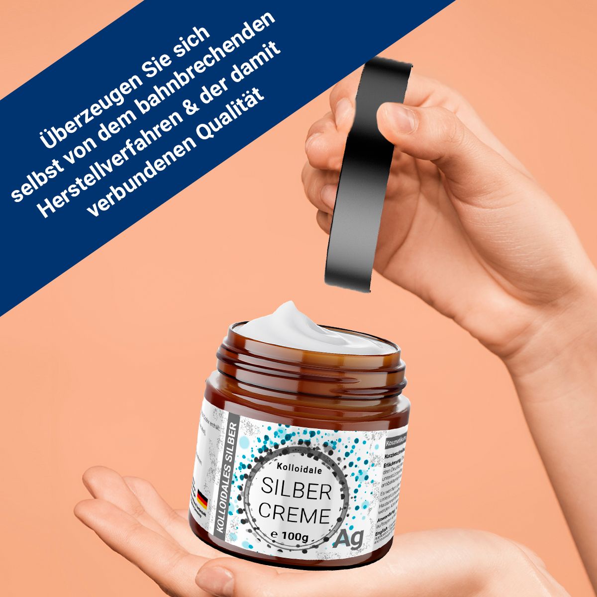 Hand hält braunes Glas mit Creme und schwarzem Deckel. Text: Kolloidale Silber Creme, e 100g, Ag.