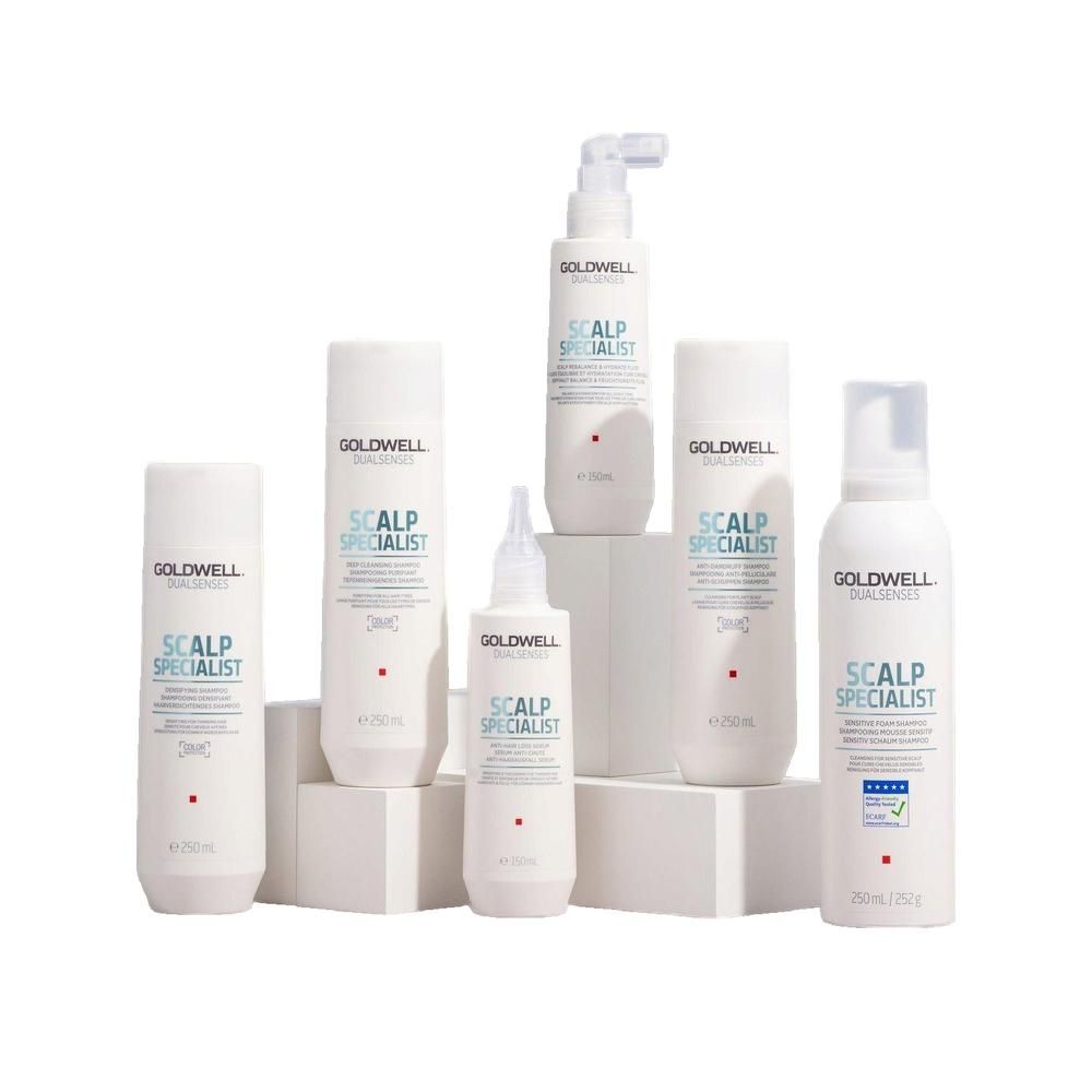 Mehrere weiße Flaschen und Flakons. Aufschrift: Goldwell Dualsenses Scalp Specialist. Verschiedene Größen. Auf Podest.