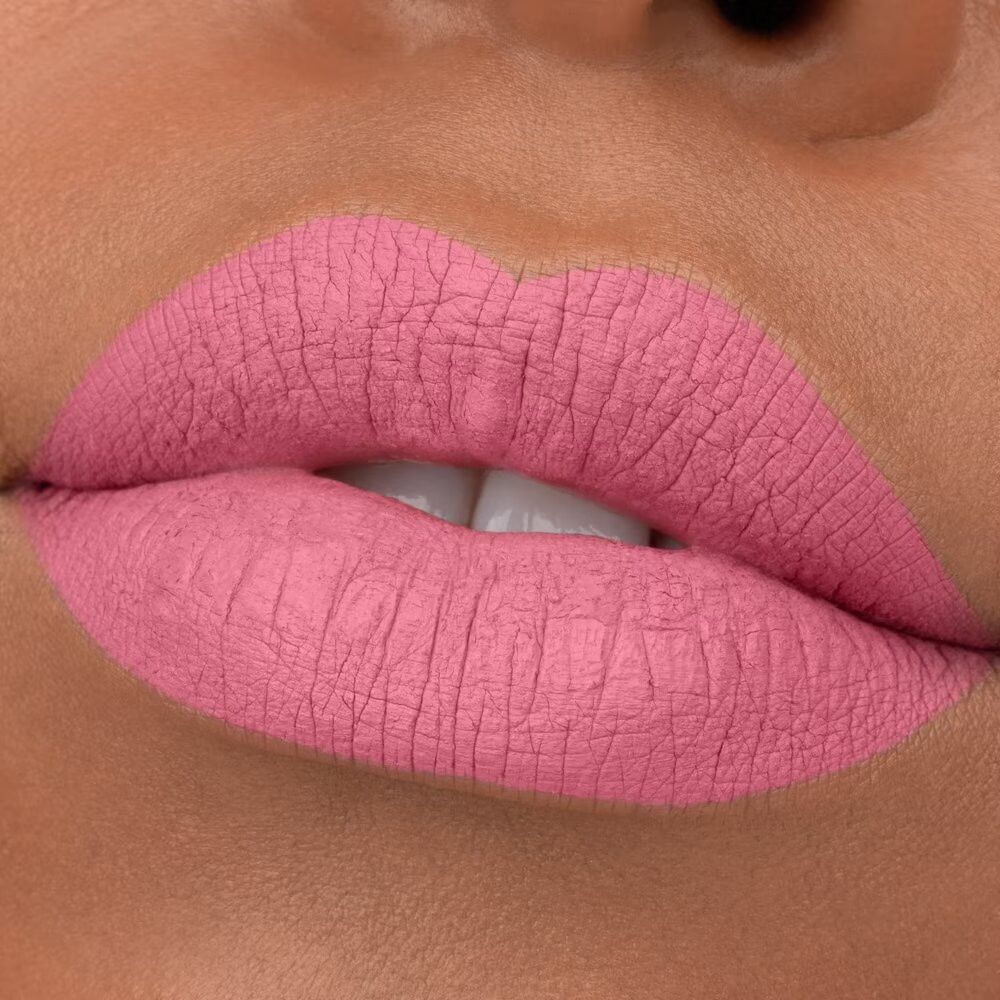 Nahaufnahme von Lippen mit rosa Lippenstift. Die Lippen sind voll und haben eine matte Textur.
