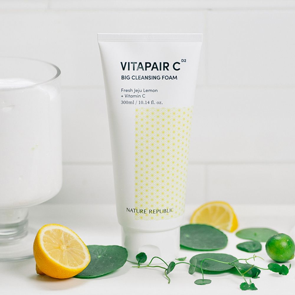Weißer Tubenreiniger mit gelbem Muster. Aufschrift: Vitapair C Big Cleansing Foam, Nature Republic. Daneben Zitrone, Blätter und ein Glas.