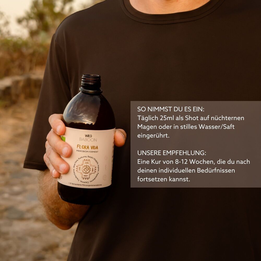 Braune Glasflasche mit Etikett, gehalten von einer Hand. Aufschrift: FLORA VIDA. Text: Täglich 25ml als Shot.