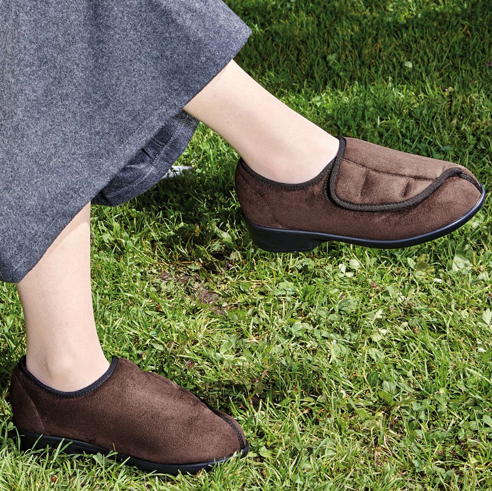 Person trägt braune Halbschuhe auf Rasen. Schuhe mit Klettverschluss. Nahaufnahme.