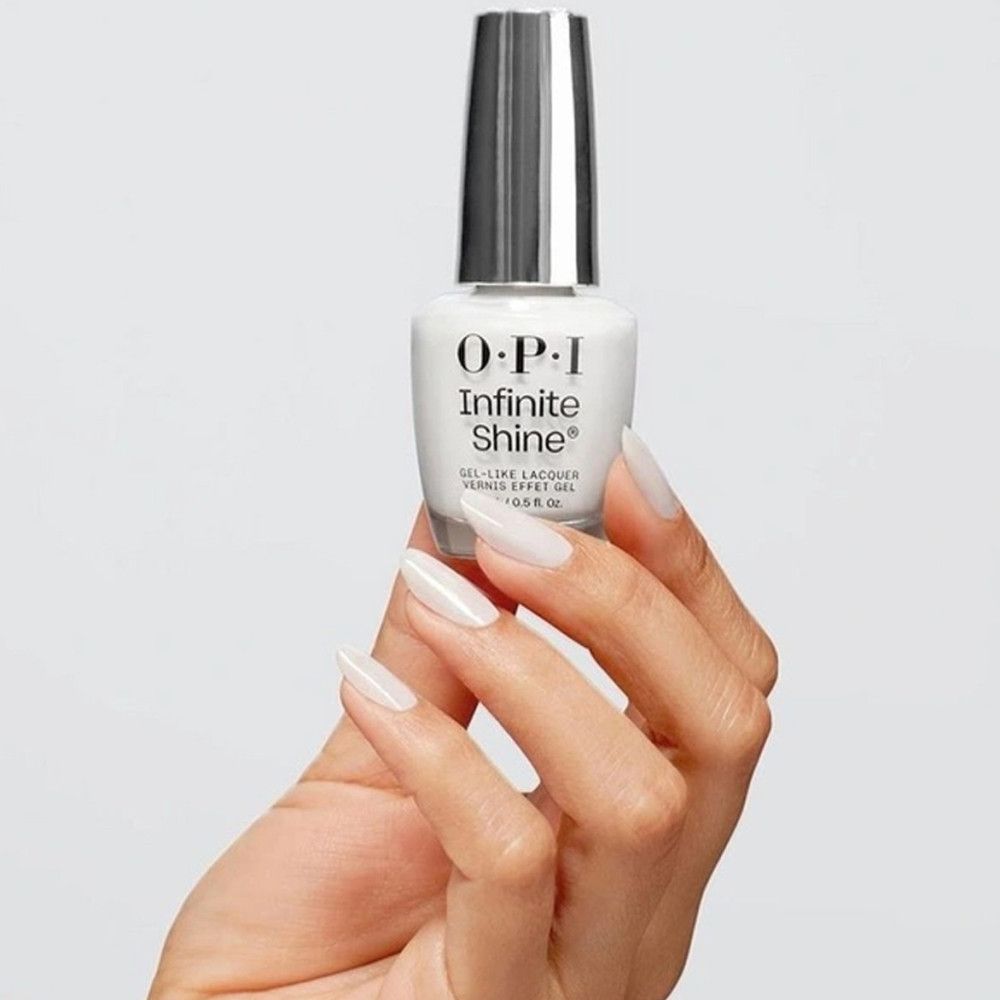 Weißer Nagellack von OPI Infinite Shine. Flasche mit silbernem Deckel. Hand hält die Flasche und lackierte Nägel.