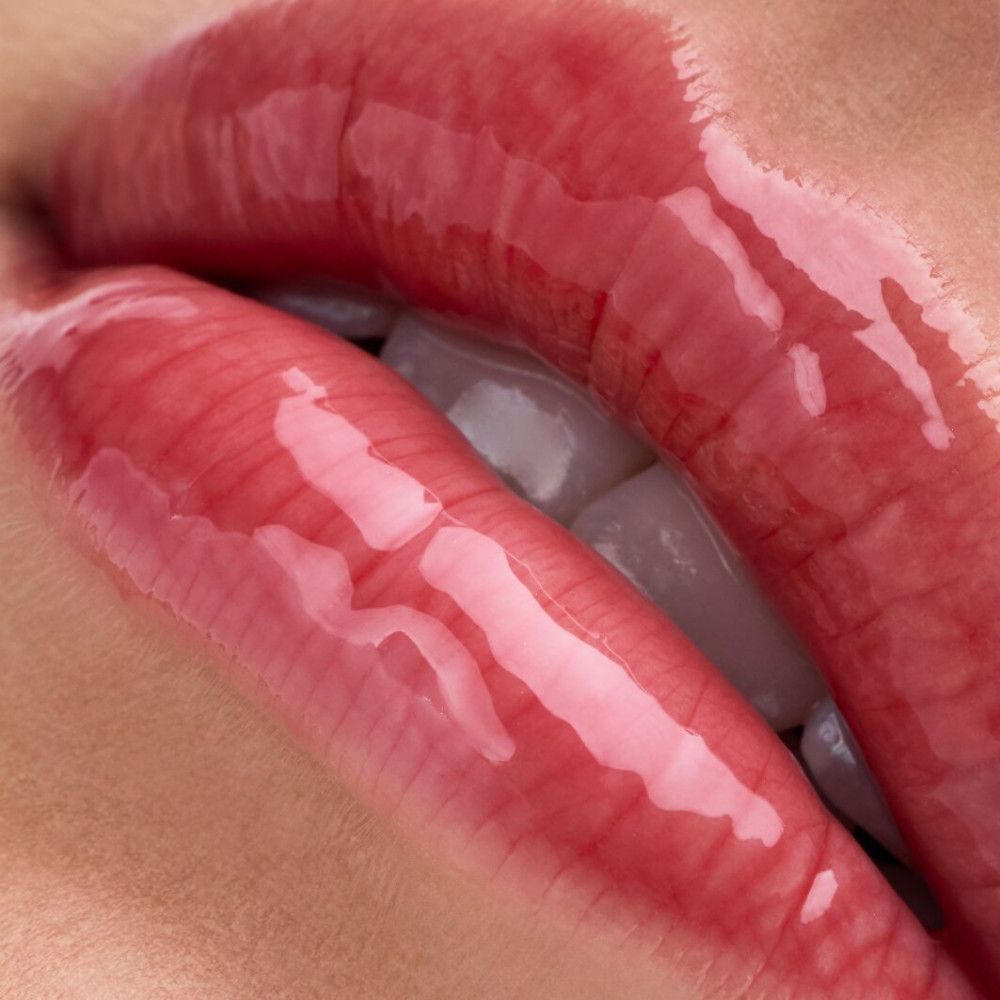 Nahaufnahme von Lippen mit glänzendem Lipgloss. Die Lippen sind rot und glänzend.