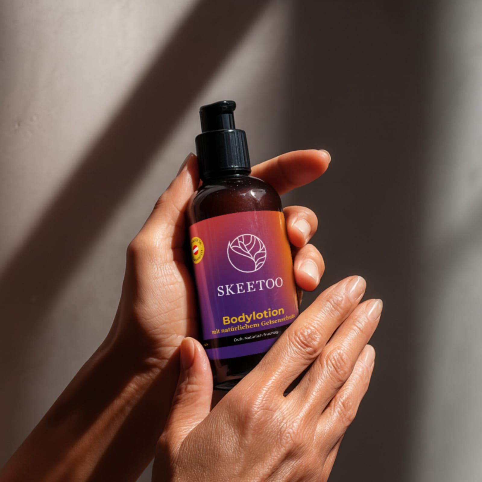 Braune Flasche mit schwarzem Pumpkopf. Etikett mit Logo und Schriftzug SKEETOO Bodylotion. Hände halten die Flasche.