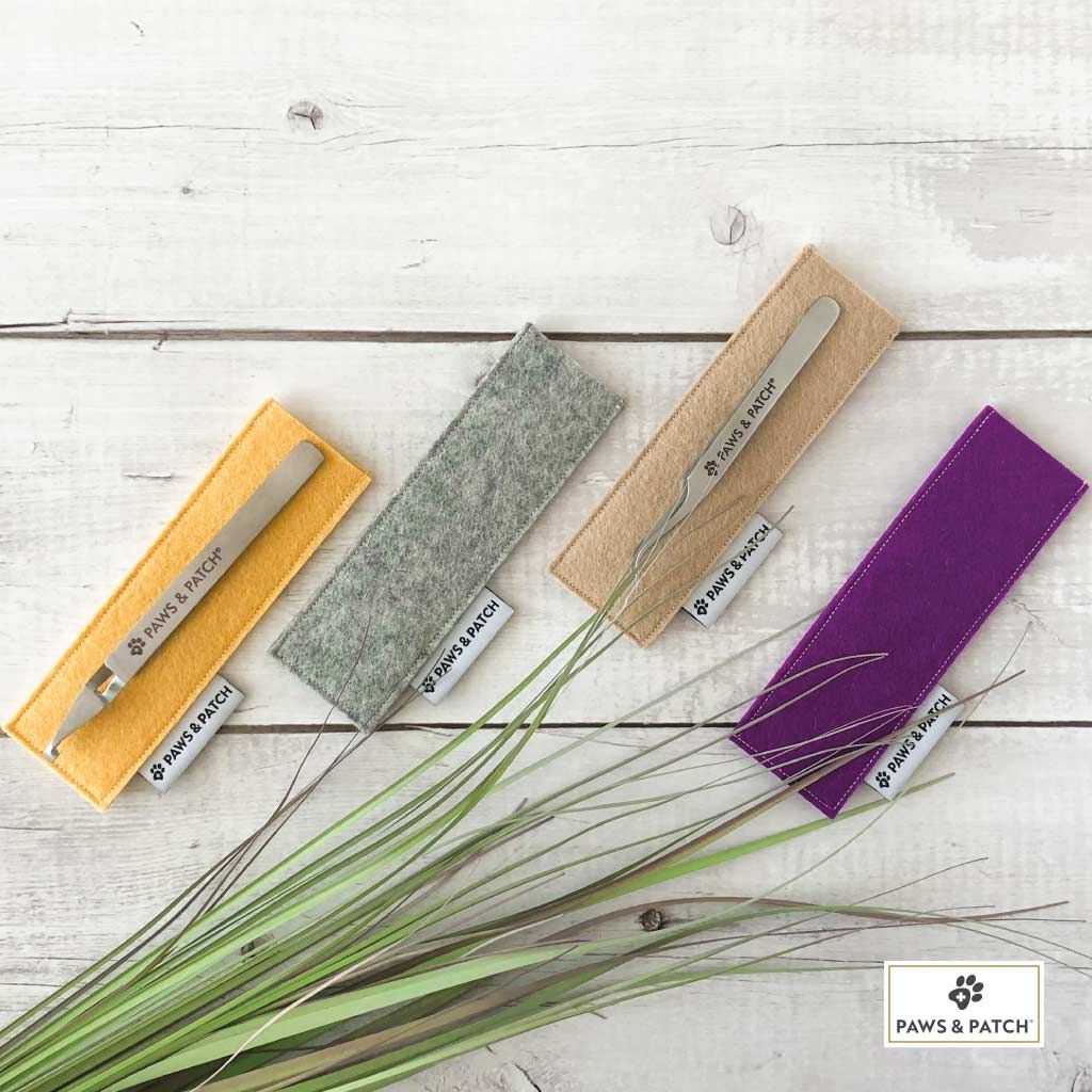 Vier Zecken-Duo-Werkzeuge mit Etuis in Gelb, Grau, Beige und Lila. Beschriftung: PAWS & PATCH.