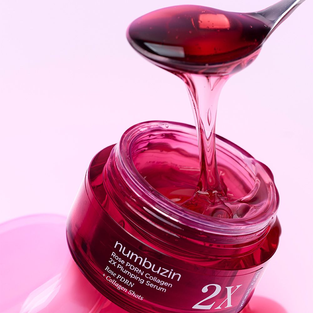 Ein Löffel mit NUMBUZIN Rose PDRN Collagen 2X Plumping Serum tropft in einen offenen roten Tiegel.