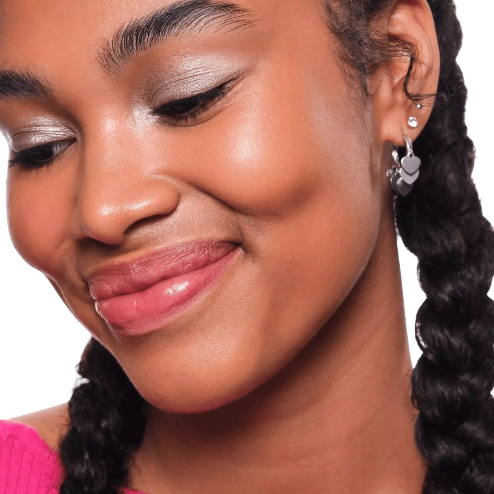 Nahaufnahme einer Frau mit geflochtenen Haaren und silbernen Ohrringen. Sie trägt Lidschatten.