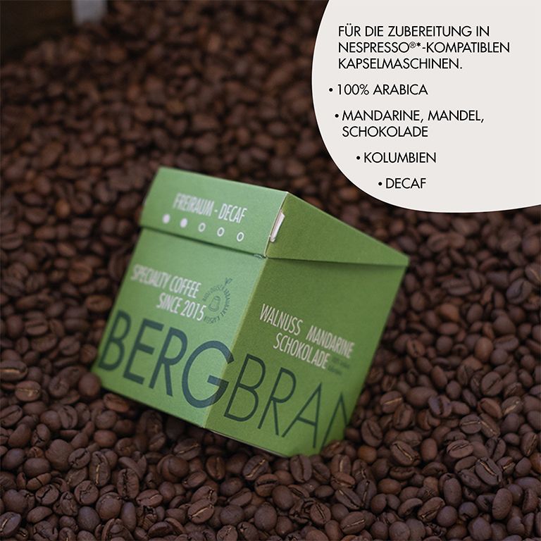 Grüne Verpackung mit BERGBRAND-Logo auf Kaffeebohnen. Text: Freiraum-Decaf, Specialty Coffee, Walnuss Mandarine Schokolade.