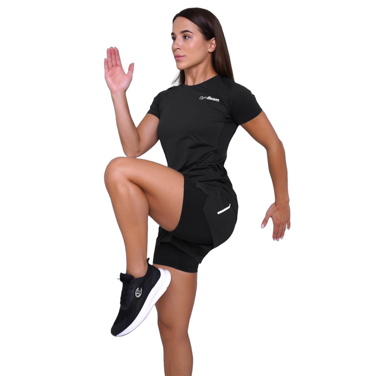 Frau in schwarzen 2-in-1-Shorts und T-Shirt, hebt ein Knie.