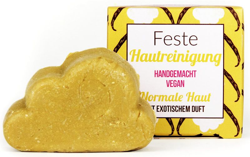 Gelb-farbiger, wolkenförmiger Festreiniger neben gelber Verpackung mit Text: Feste Hautreinigung, Handgemacht, Vegan, Normale Haut.