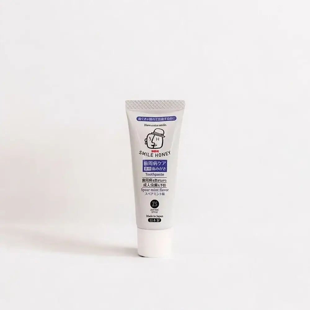 Zahnpasta-Tube "SMILE HONEY". Graue Tube mit weißem Deckel. "Spear mint flavor" ist sichtbar.
