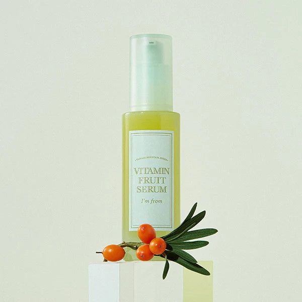 Gelbe Flüssigkeit in einer Flasche mit weißem Etikett. Aufschrift: Vitamin Fruit Serum, i'm from. Mit Zweig und Beeren.