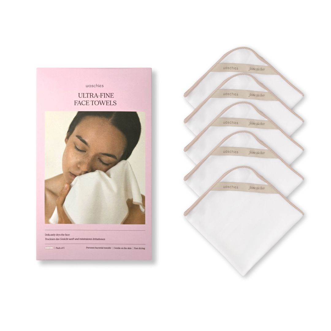 Produktverpackung und 5 weiße Tücher. Verpackung: ULTRA-FINE FACE TOWELS. Beige Stoffschlaufe mit Schriftzug.
